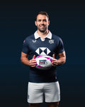 Athlete in navy HK7s home replica jersey holding a rugby ball against a dark backdrop