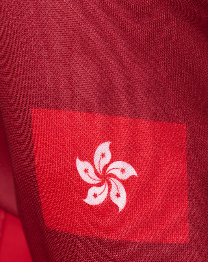 Close-up of red knit fabric with a white floral crest on a red square patch