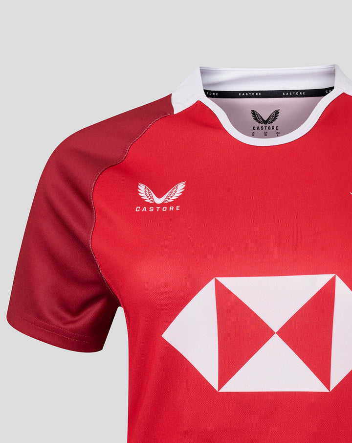 Shoulder and chest view of red HKCR women’s away jersey with a white crest on the left chest and a bold white diamond sponsor graphic on the front