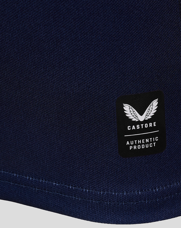 Close up of navy home replica jersey fabric with a black Castore authentication patch near the hem