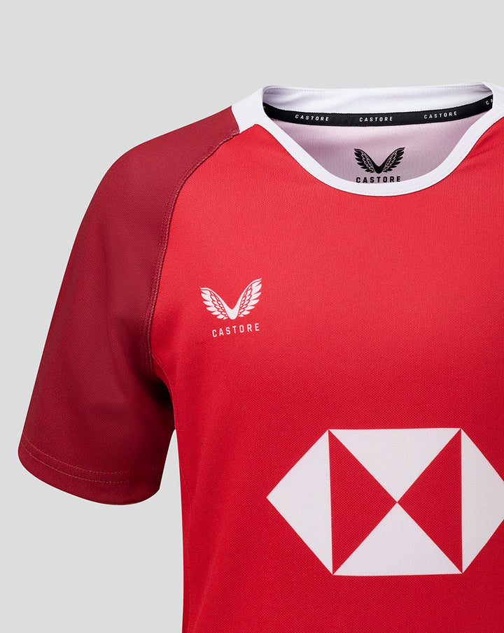 Front view of red junior away jersey with Castore logo on the chest and a large white diamond sponsor graphic