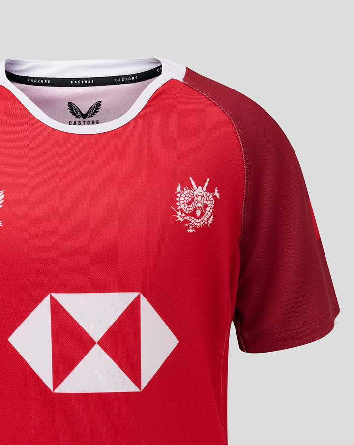 Red jersey upper torso with white crest on the chest and a large white geometric sponsor symbol below