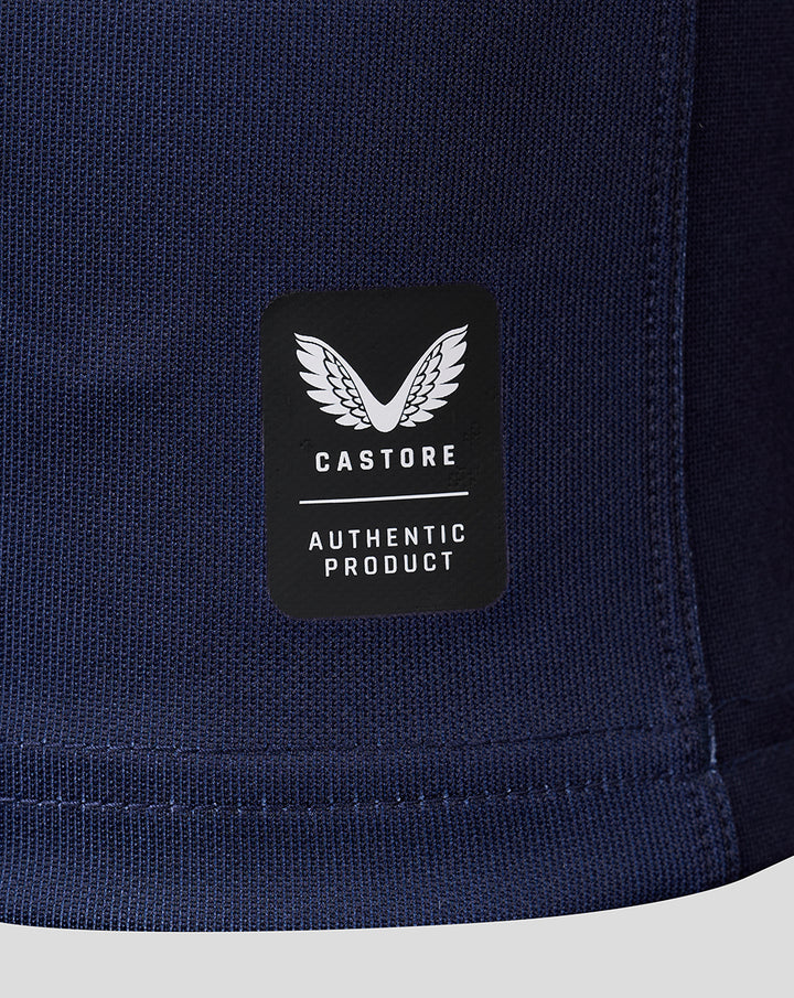 Close-up of navy jersey hem featuring a black Castore Authentic Product patch with a white winged logo.