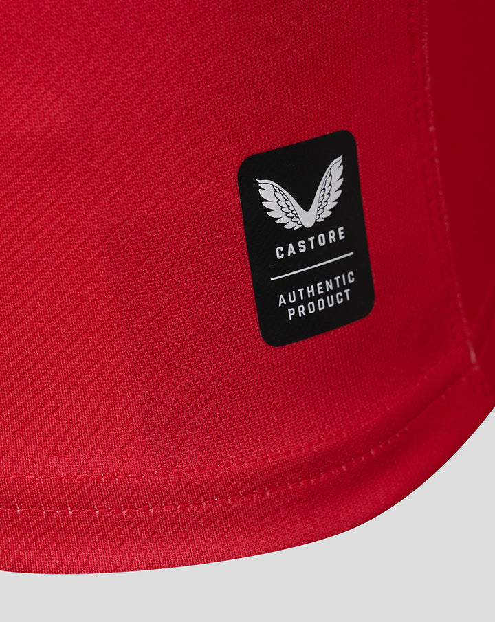 Red jersey close up with black Castore authentic product sticker on the fabric near the hem